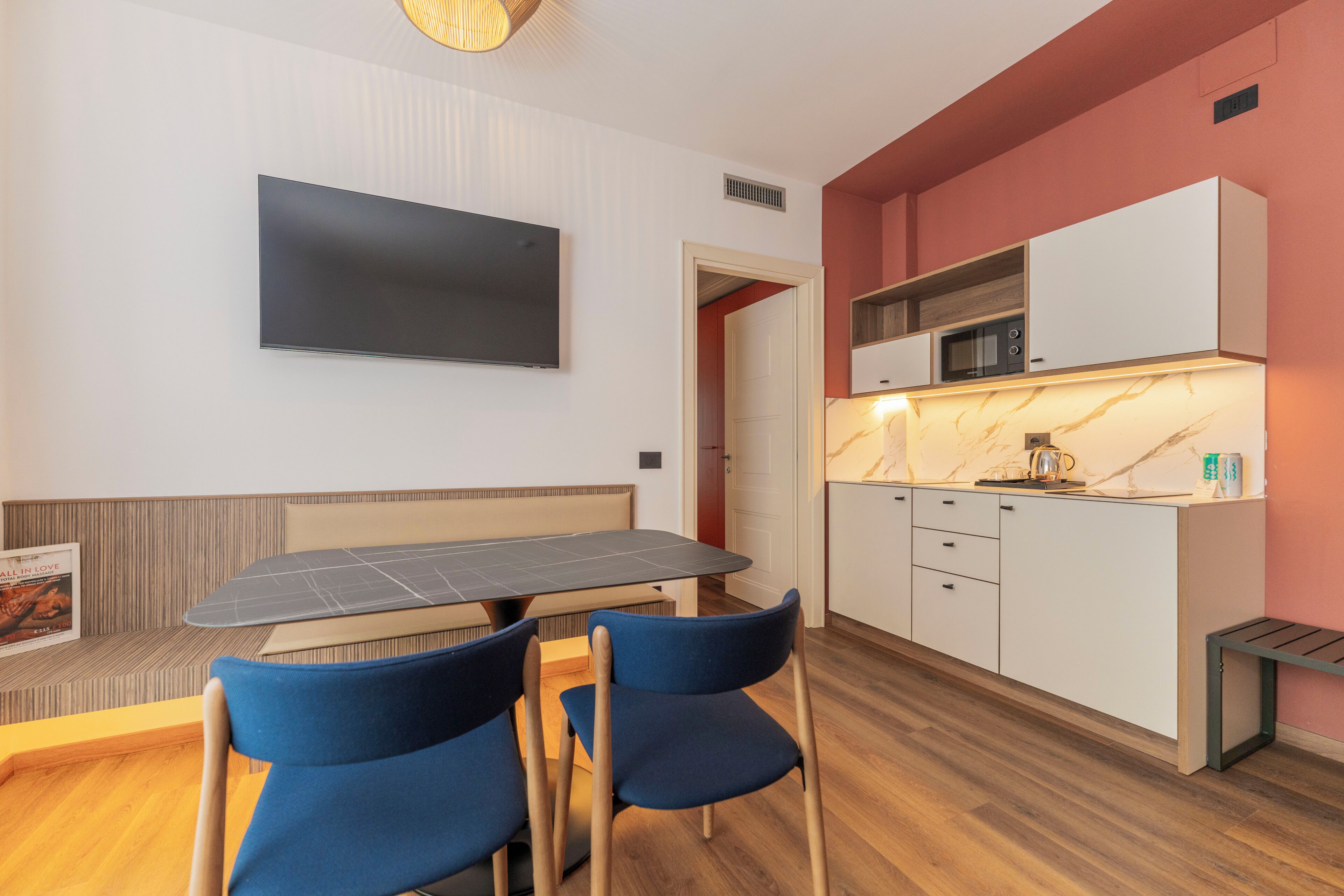 A modern kitchen with white cabinets, a microwave, and a marble countertop.