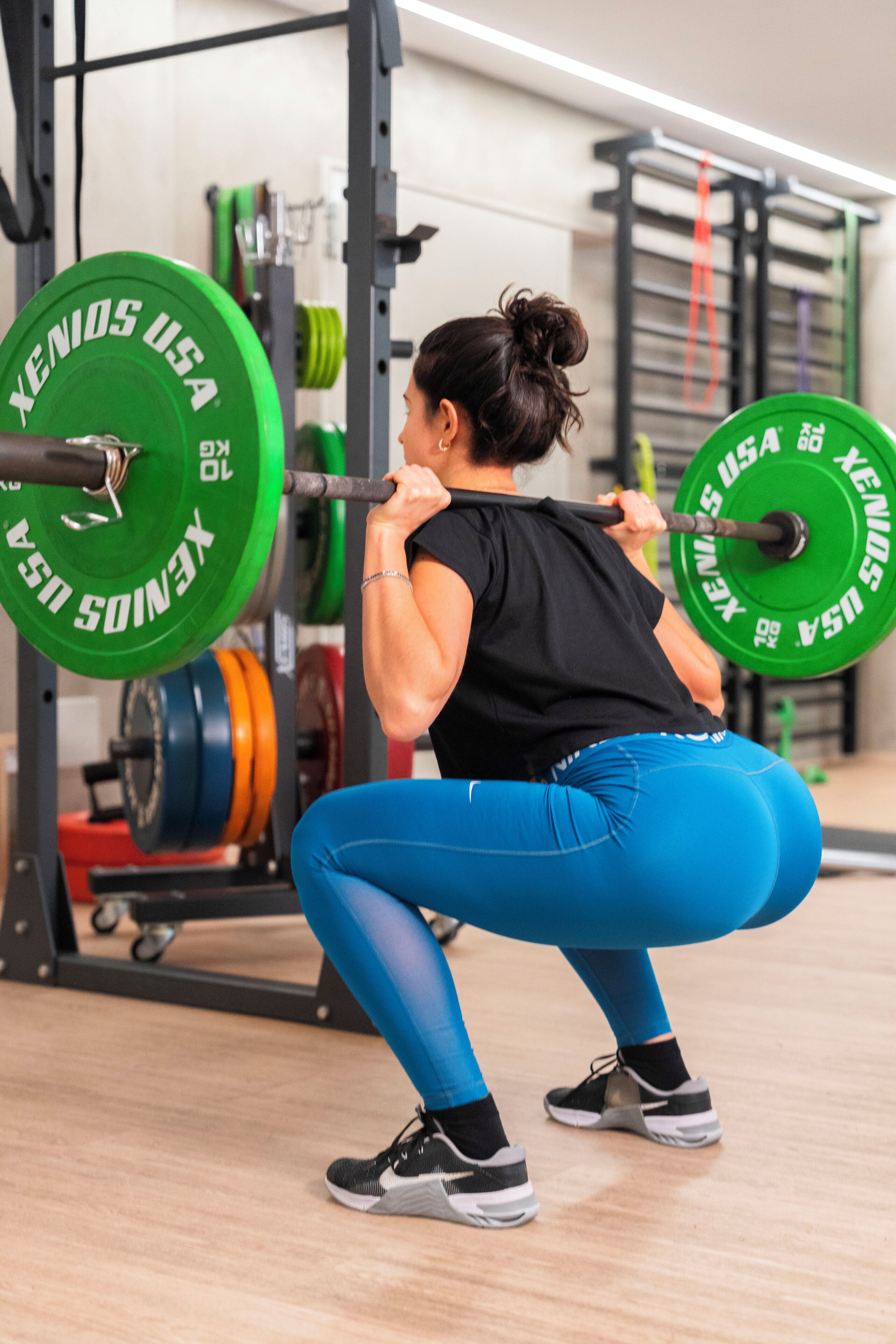 Une personne effectuant un squat avec une barre chargée de disques de poids.