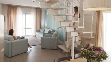 A modern living room with a staircase, a sofa, and a dining area.