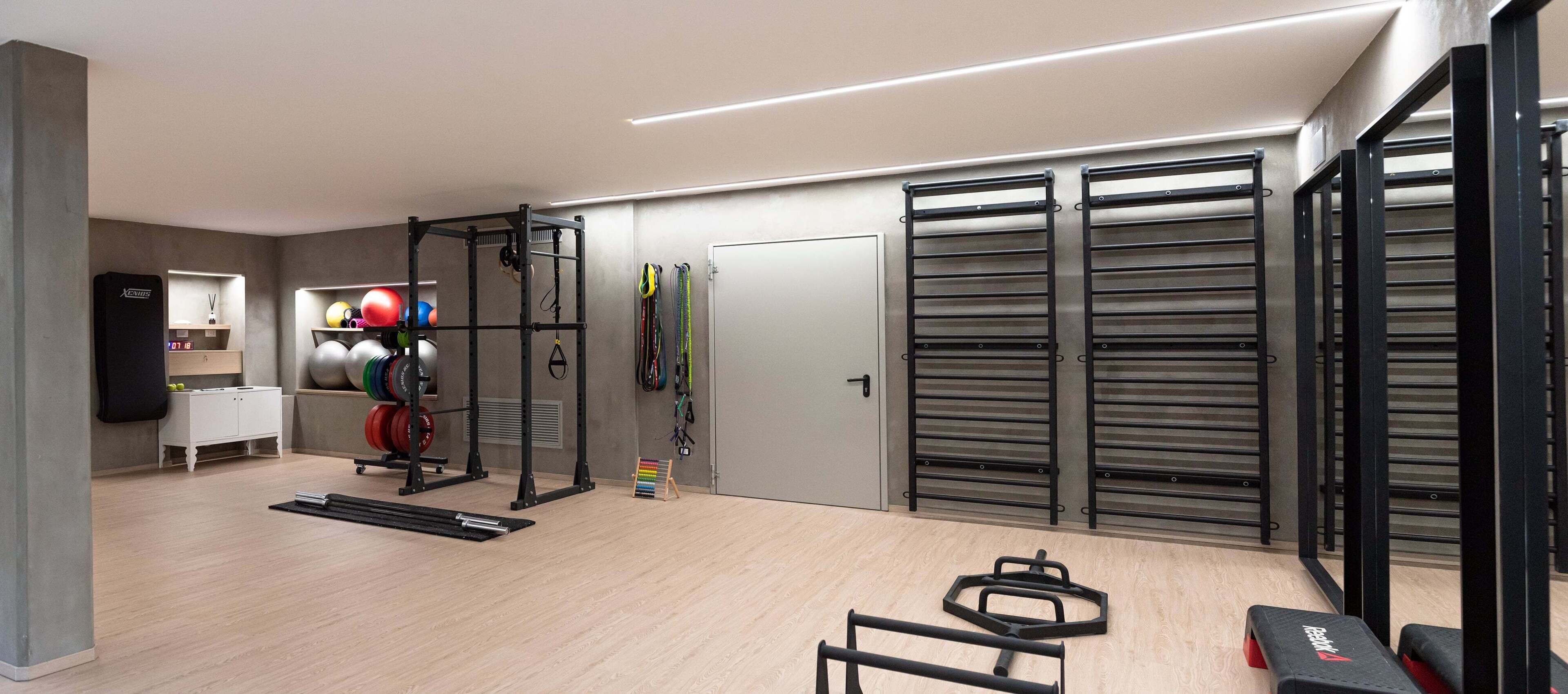 Un gimnasio con equipo de levantamiento de pesas, barra de dominadas y banco.