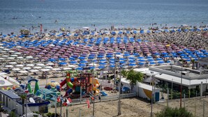 Una playa con numerosos paraguas y un parque acuático.