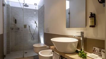 Un bagno moderno con doccia vetrata, un WC e un lavandino capiente con specchio sopra.