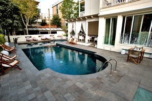 A swimming pool with lounge chairs and a covered seating area.