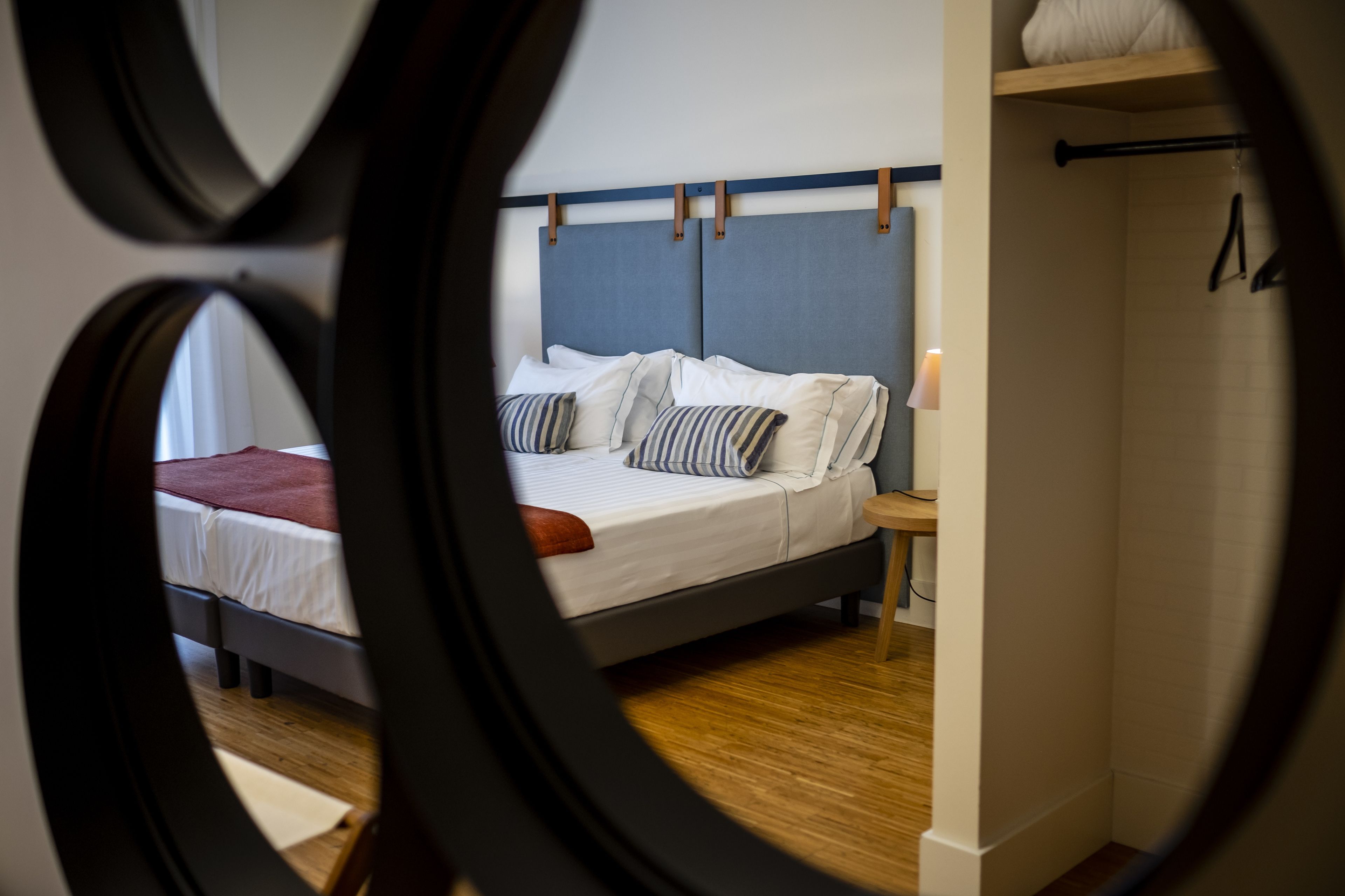 A bedroom with a bed, pillows, a nightstand, and a wall-mounted shelf.