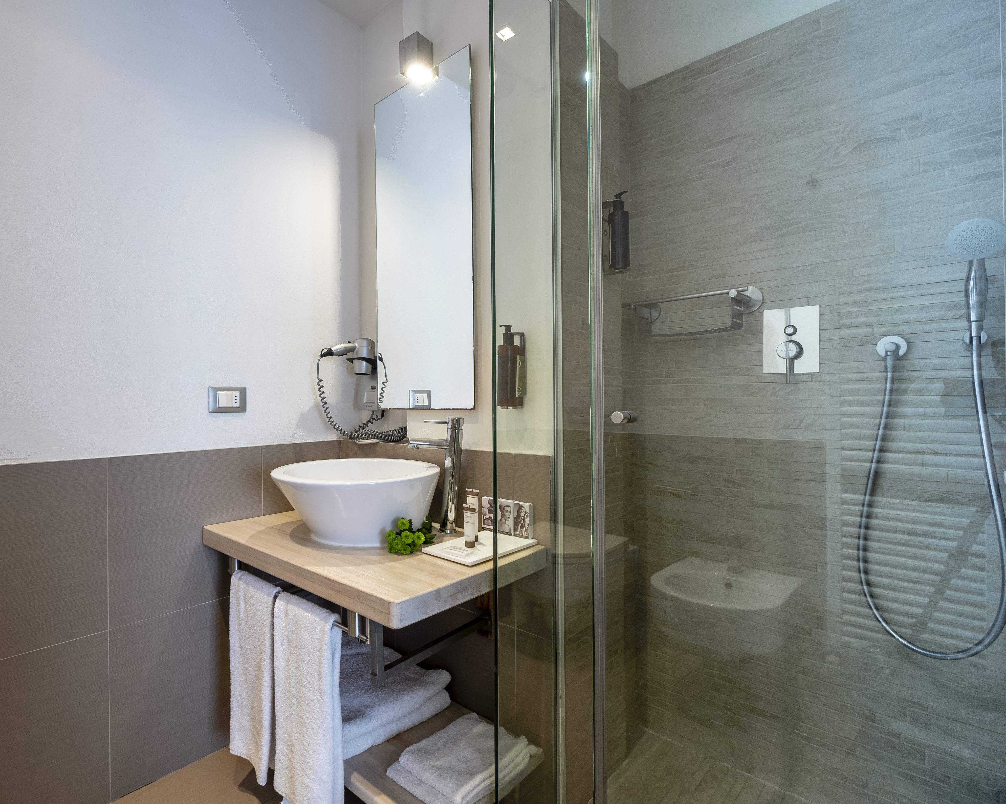 A modern bathroom with a glass-enclosed shower, a large sink, and a mirror above the vanity.