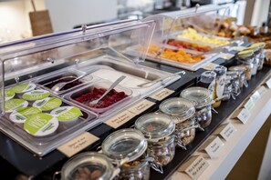 A buffet with various food items and condiments, including labeled containers of yogurt and sauces.