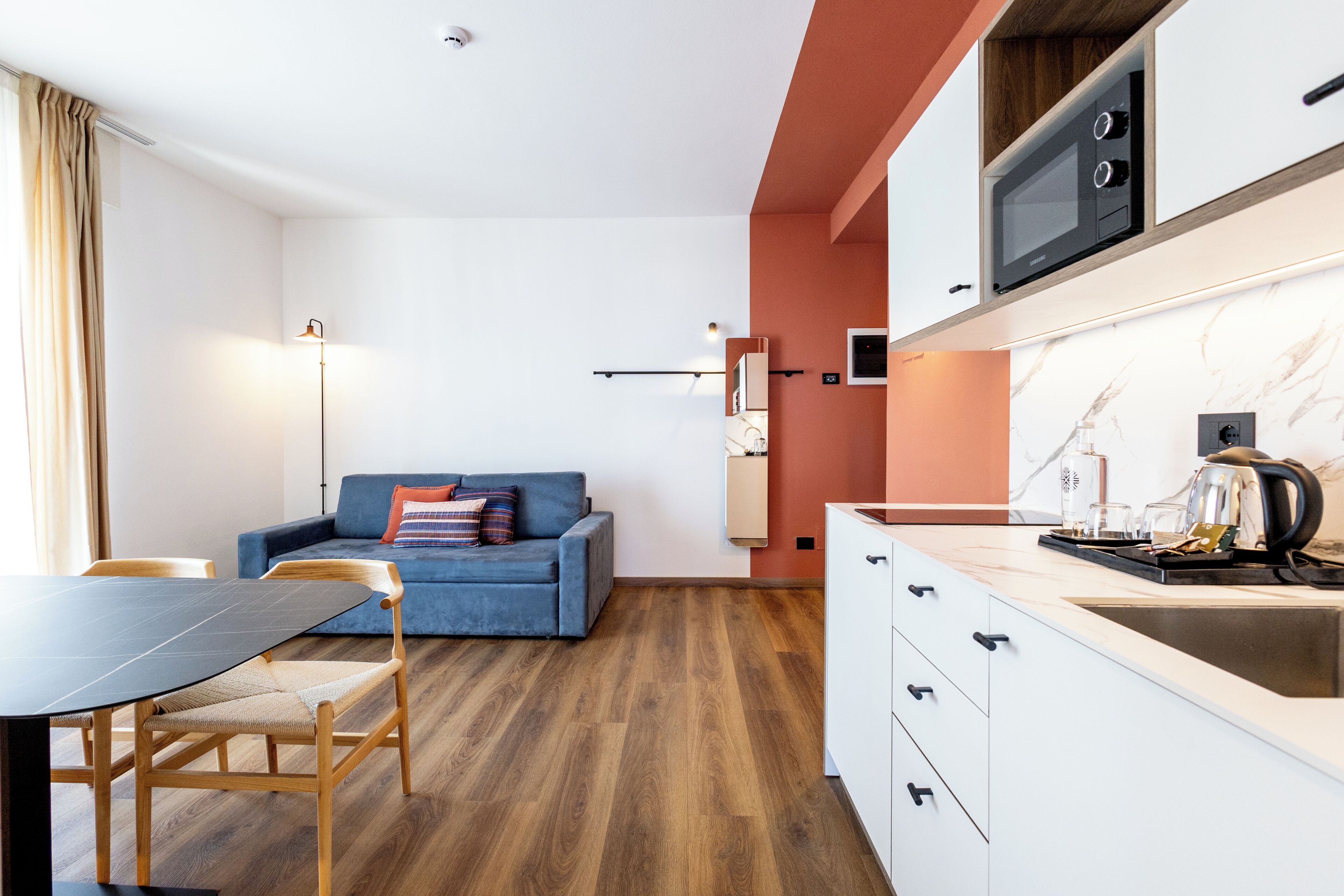 A modern kitchen with a microwave, a sink, and a dining area with a table and chairs.