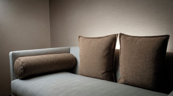 A corner of a room with a grey sofa and two brown pillows.