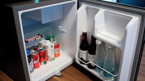 An open refrigerator with snacks, drinks, and bottles.