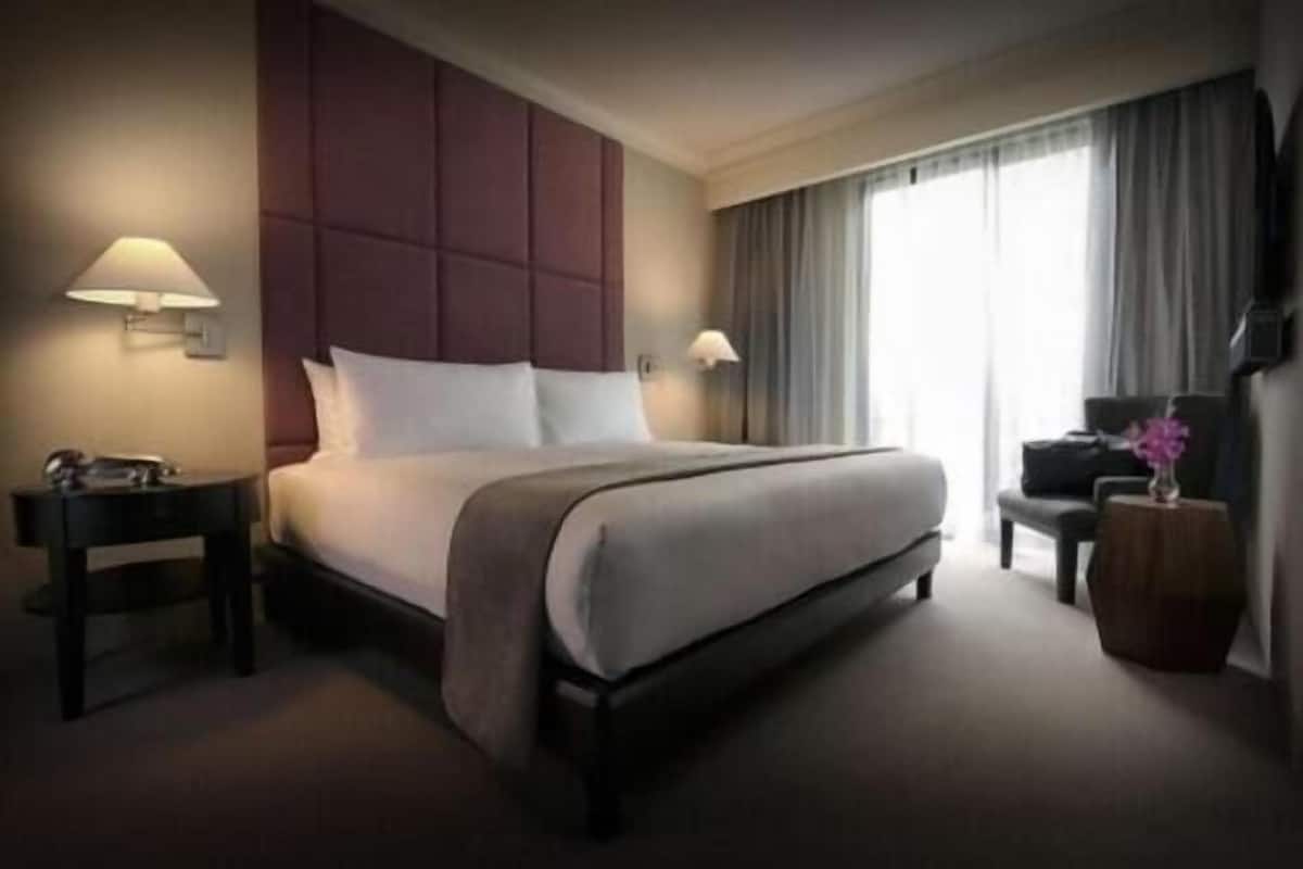 Hotellihuone, jossa on suuri sänky, kaksi yöpöytää, työpöytä ja tuoli.
