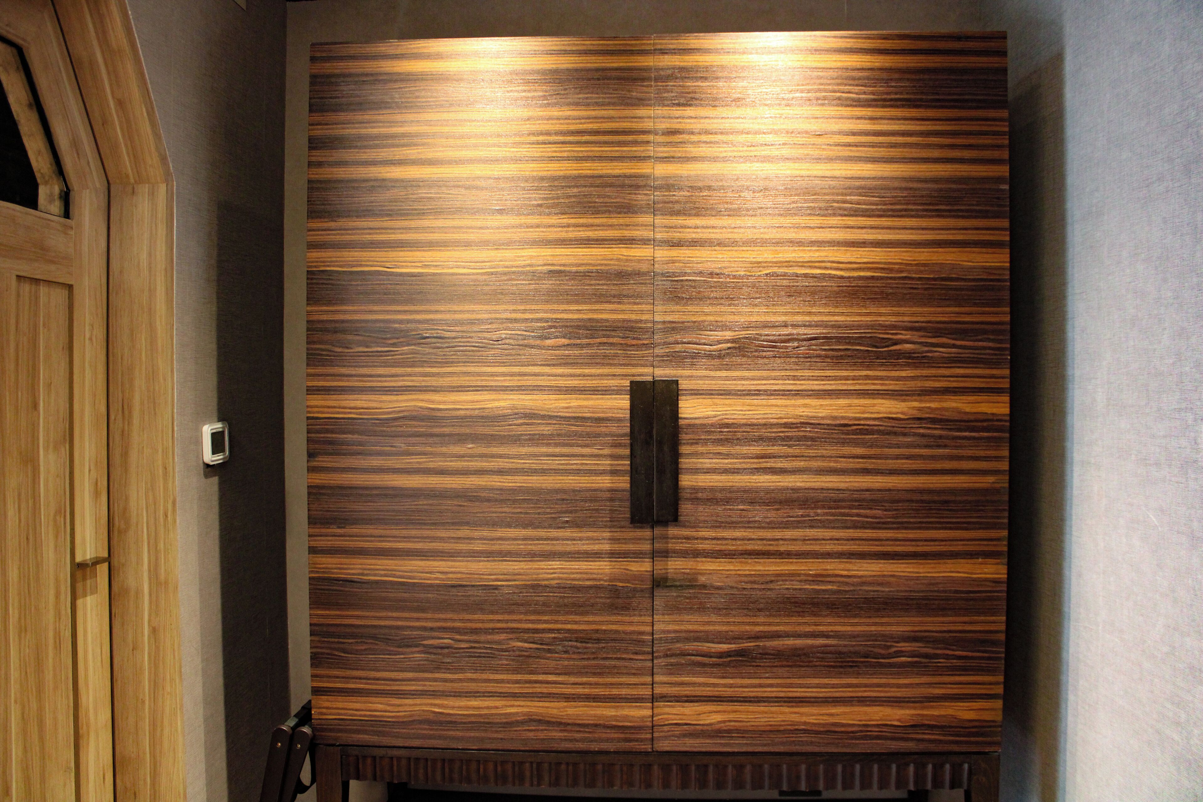 A large wooden wardrobe with a central handle and a textured surface.