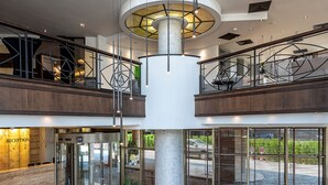 A spacious lobby with a central column, a reception desk, and a seating area with sofas and a coffee table. - Hotel Vega Sofia (Sofia)