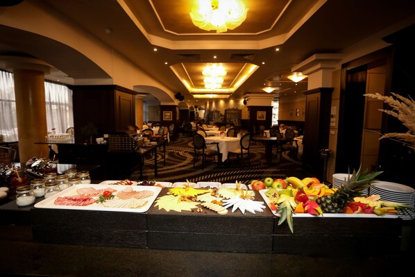 A buffet area with various food items and a dining room in the background.