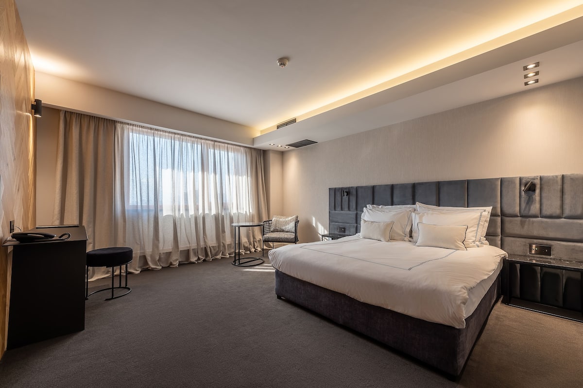 A modern hotel room with a large bed, a desk, and a chair.