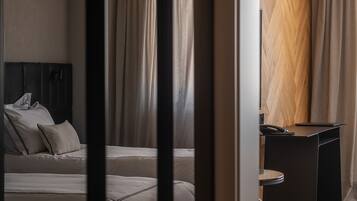 A modern hotel room with a bed, a desk, and a herringbone-patterned wall.