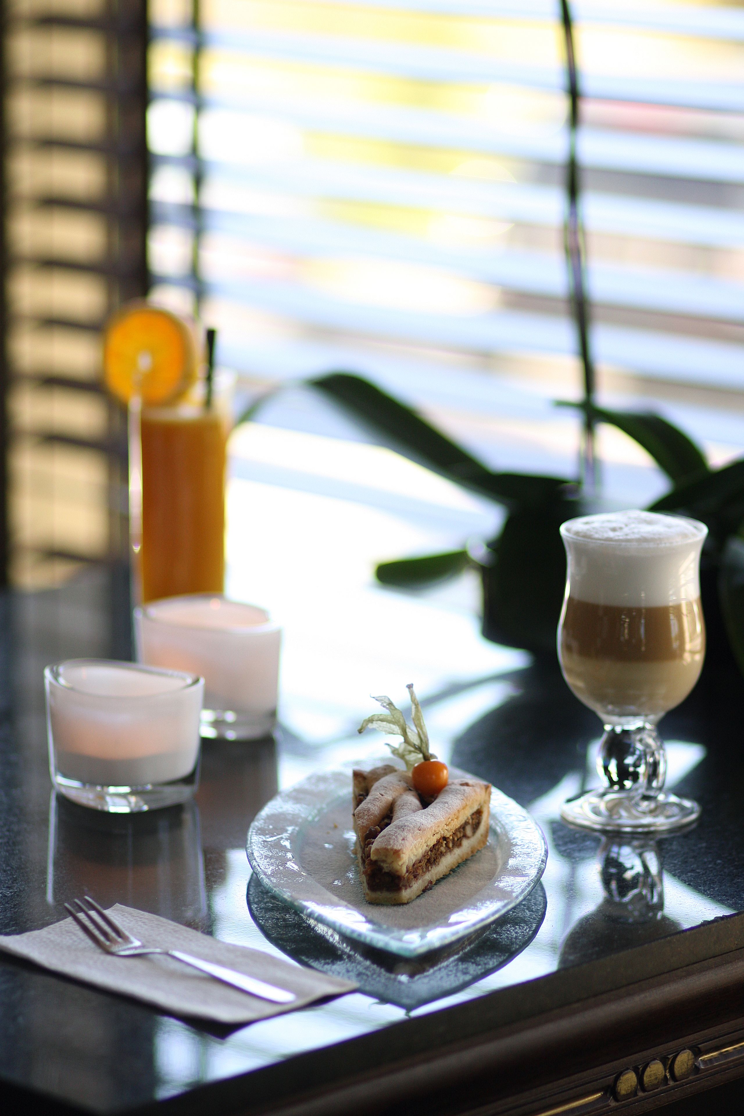 A table with a dessert, a glass of coffee, and a glass of orange juice.