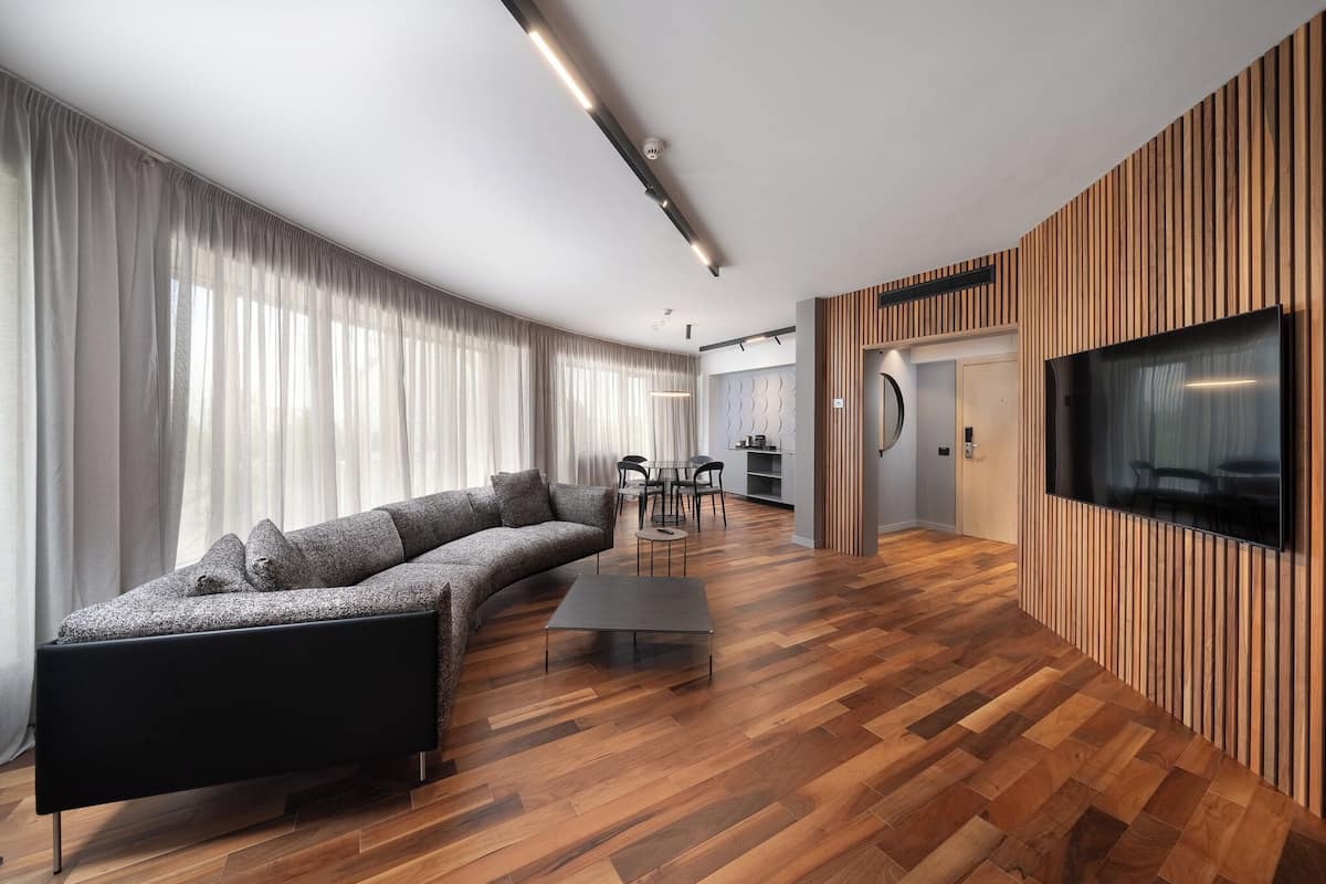A modern living room with a sectional sofa, a coffee table, and a TV mounted on a wooden wall.