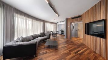Una sala de estar moderna con un sofá seccional, una mesa de centro y un televisor montado en una pared de madera.