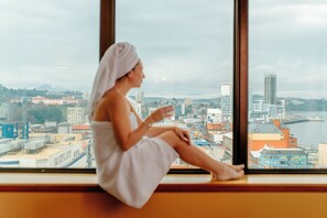 Eine Person sitzt an einem Fenster mit Blick auf die Stadt.