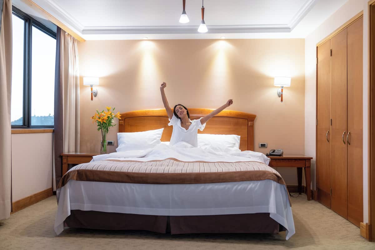 Habitación de hotel con una cama grande, cabecera de madera, mesitas de noche, escritorio y armario.