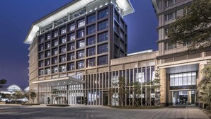A modern multi-story building with a prominent glass facade and a covered entrance area. - Pullman Guangzhou Baiyun Airport (Guangzhou)