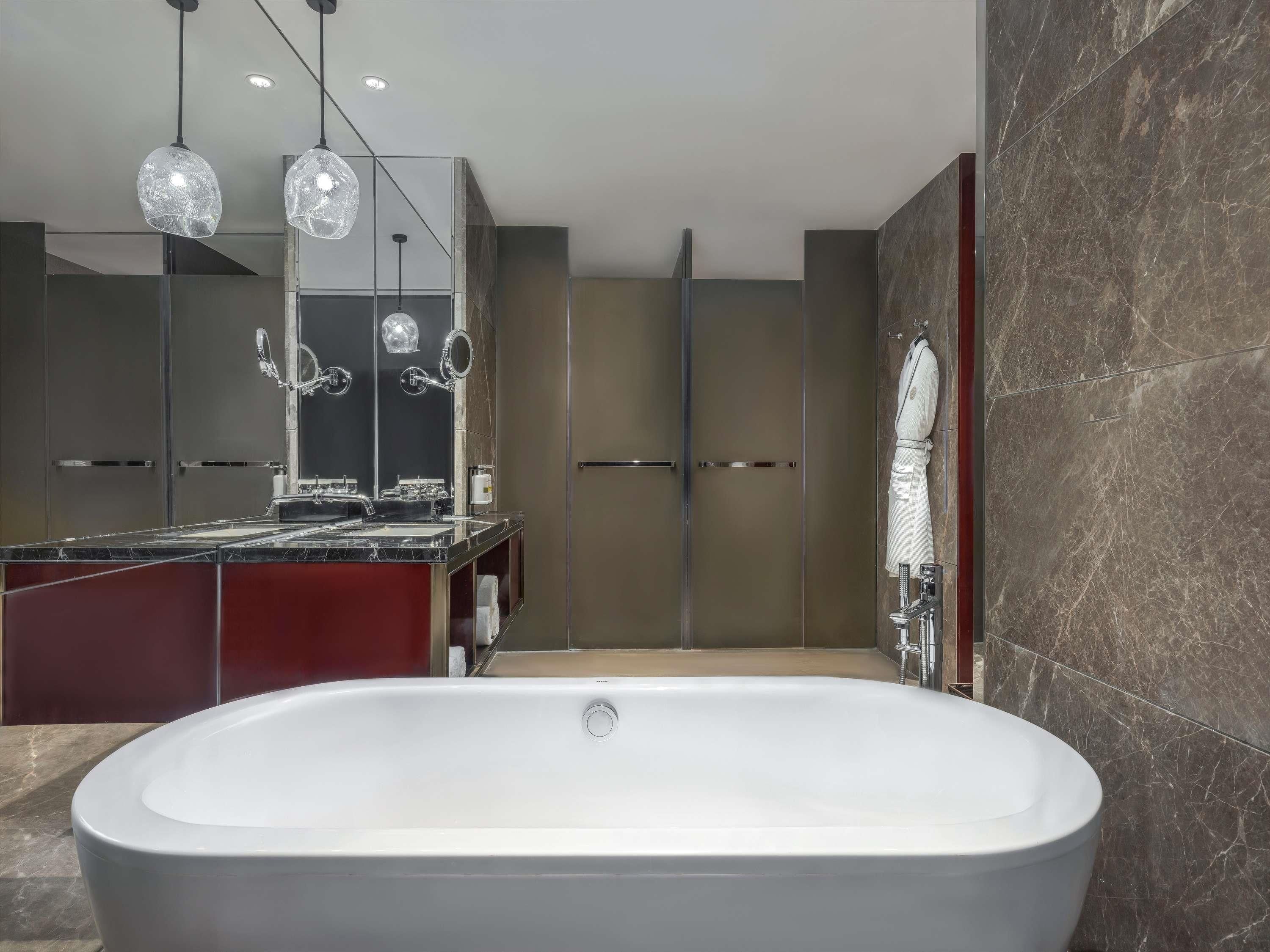 A modern bathroom with a freestanding bathtub, a large mirror, and a vanity with a marble countertop.