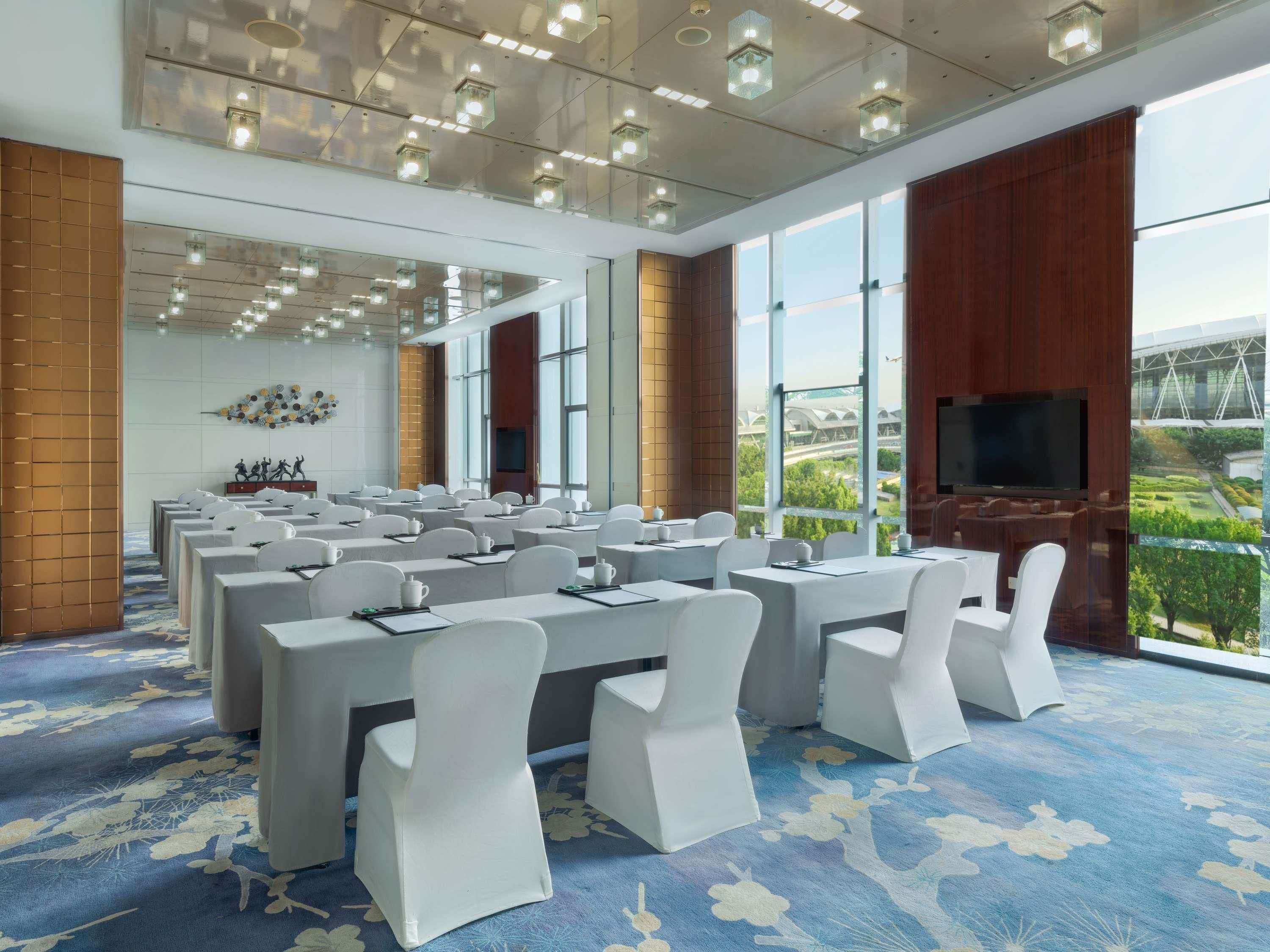 A conference room with tables and chairs, large windows, and a television.
