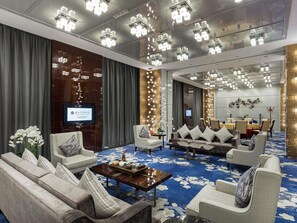 A hotel lobby with a large seating area, a television screen, and a decorative wall. - Pullman Guangzhou Baiyun Airport (Guangzhou)