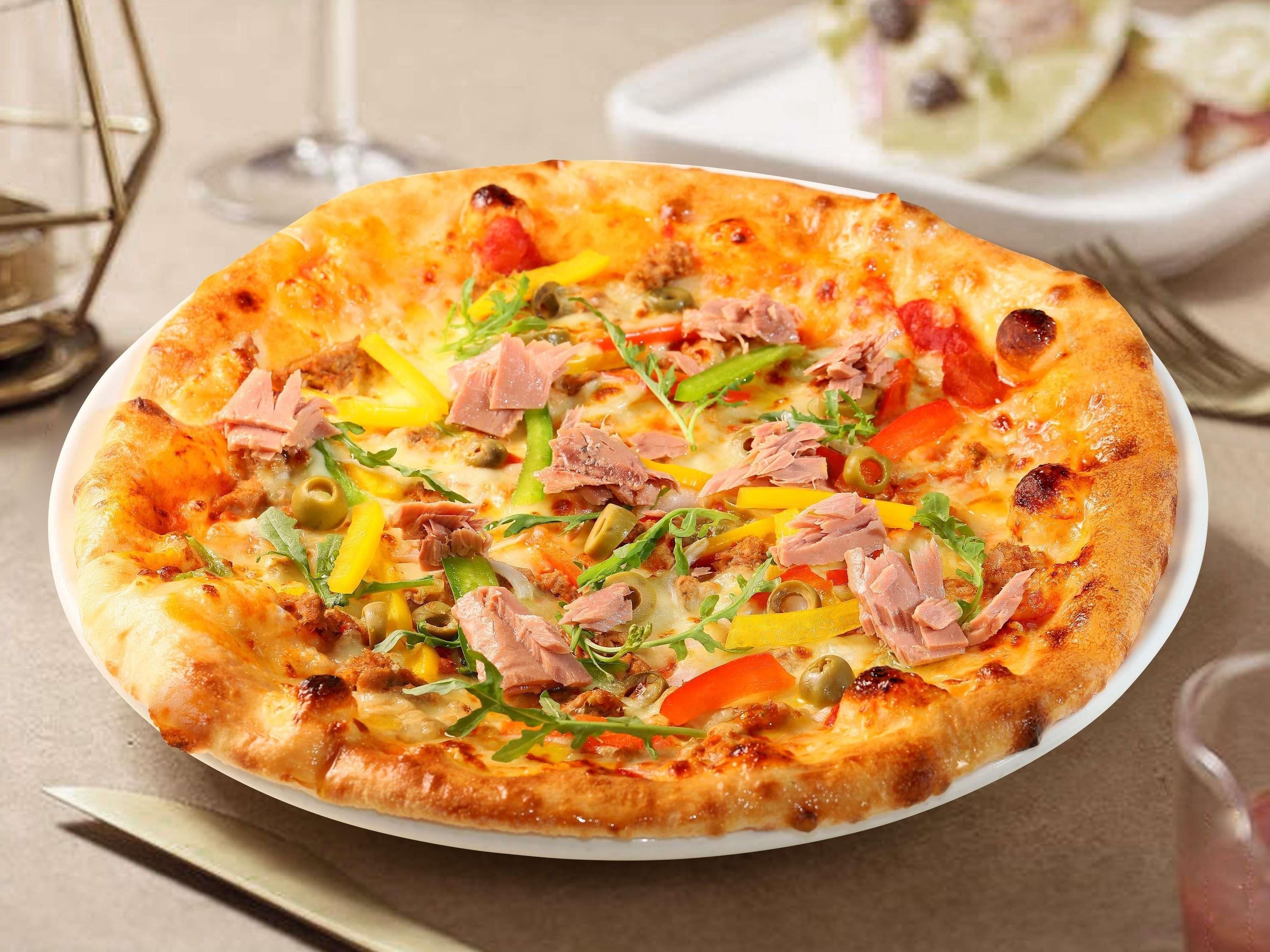 Una pizza con diversos ingredientes servida en un plato blanco.