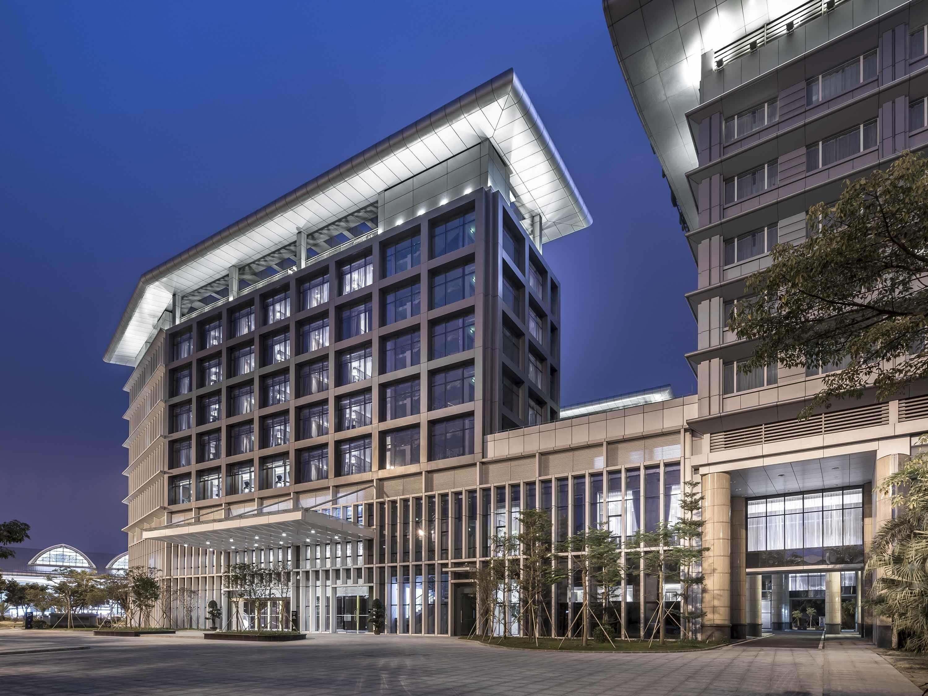 A multi-story building with a modern architectural design, featuring a prominent glass facade and a covered entrance area.