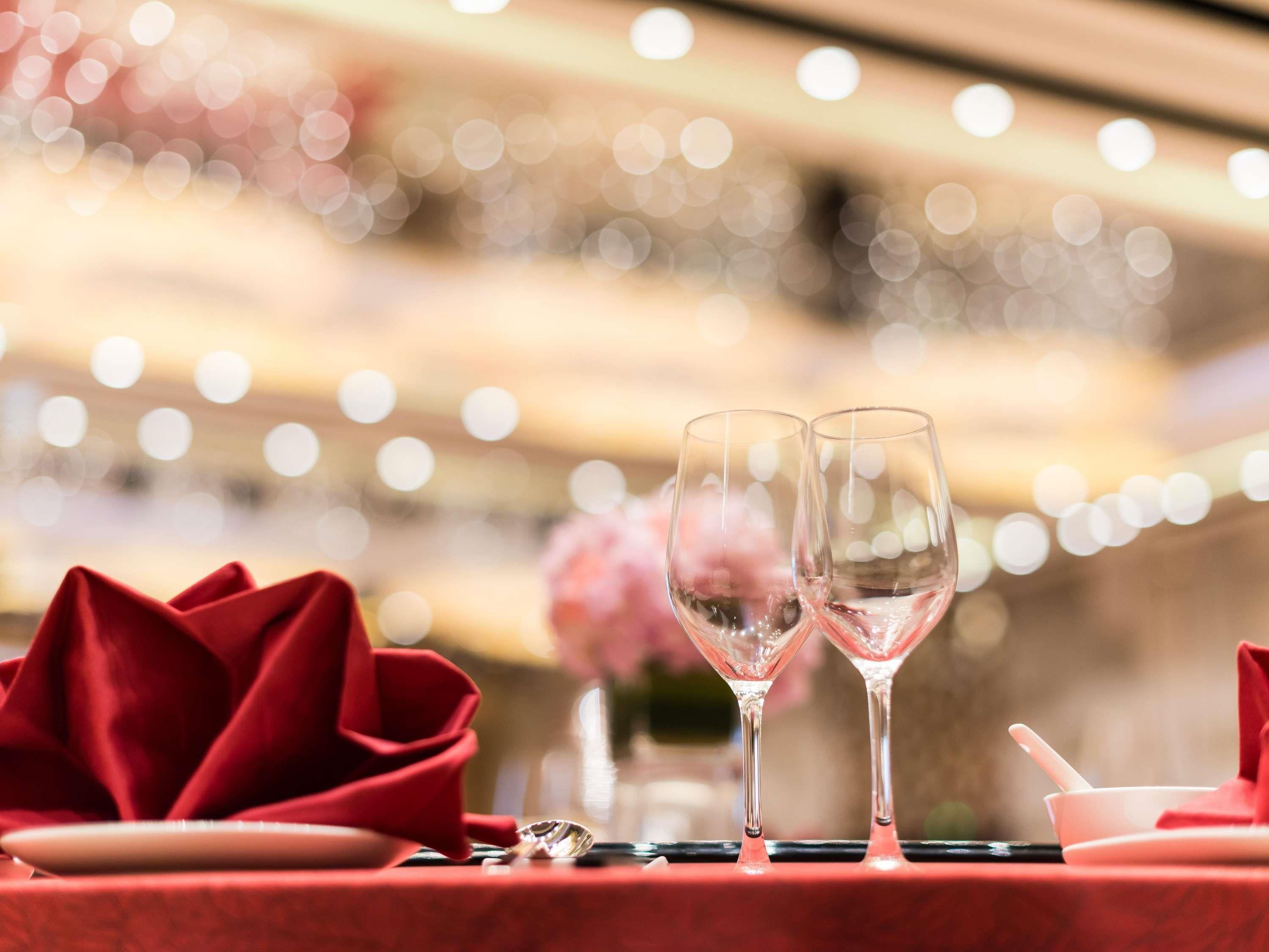 A table set with two clear glasses, a red rose, and a white bowl with a spoon.