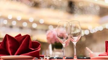 A table set with two clear glasses, a red rose, and a white bowl with a spoon.