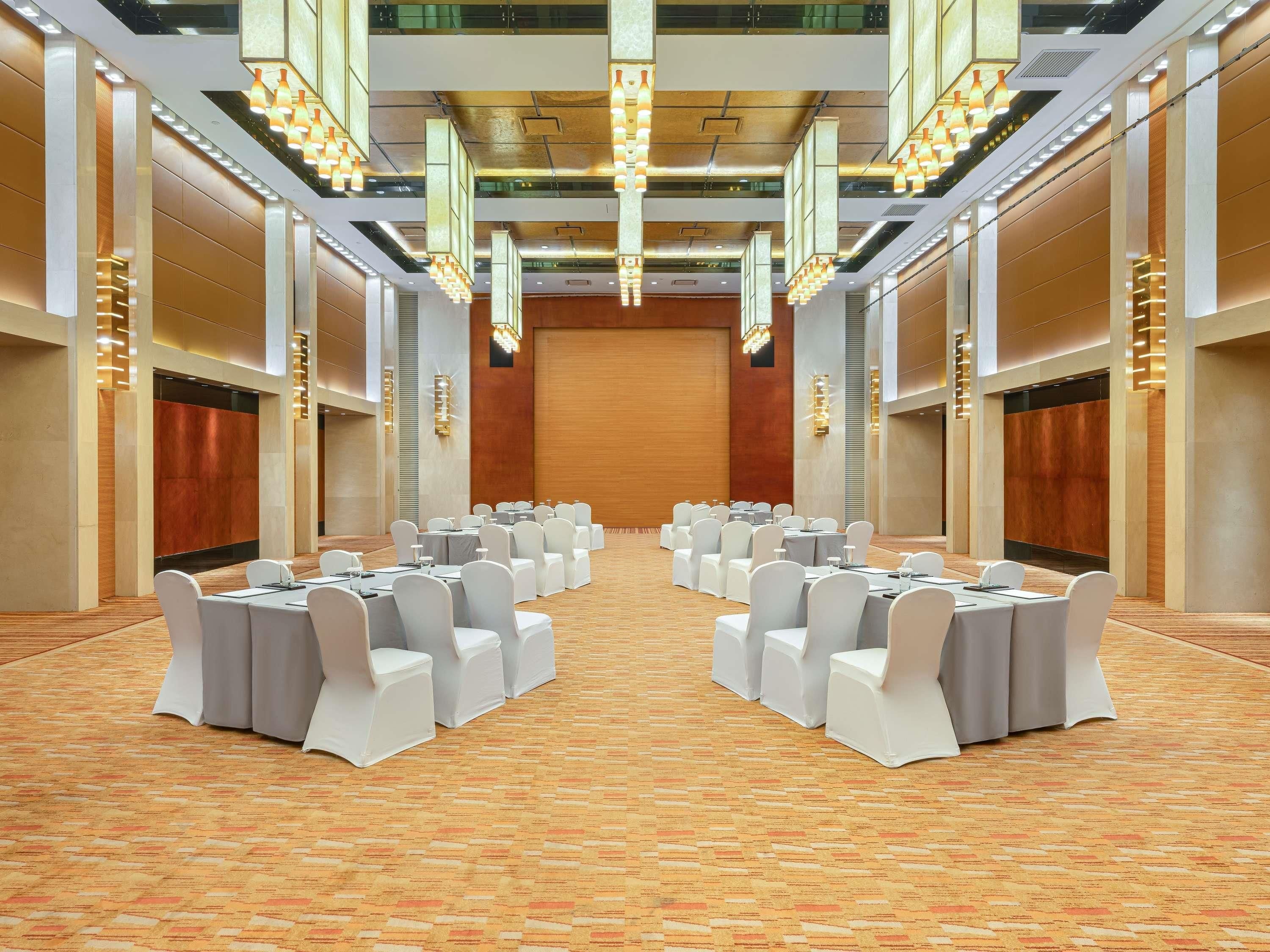 A conference room with rows of tables and chairs, a patterned carpet, and modern lighting fixtures.