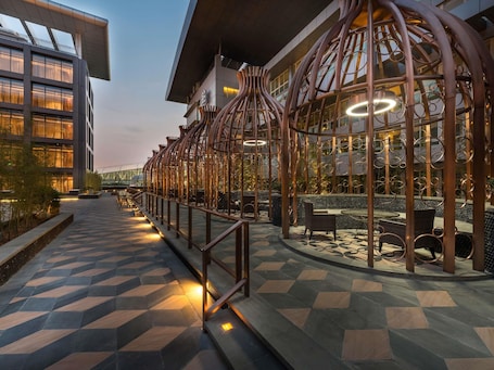 Un bâtiment moderne doté d’un sol carrelé aux motifs géométriques, d’une clôture en métal ornée de motifs circulaires et d’un espace extérieur aménagé pour s’asseoir.. Pullman Guangzhou Baiyun Airport