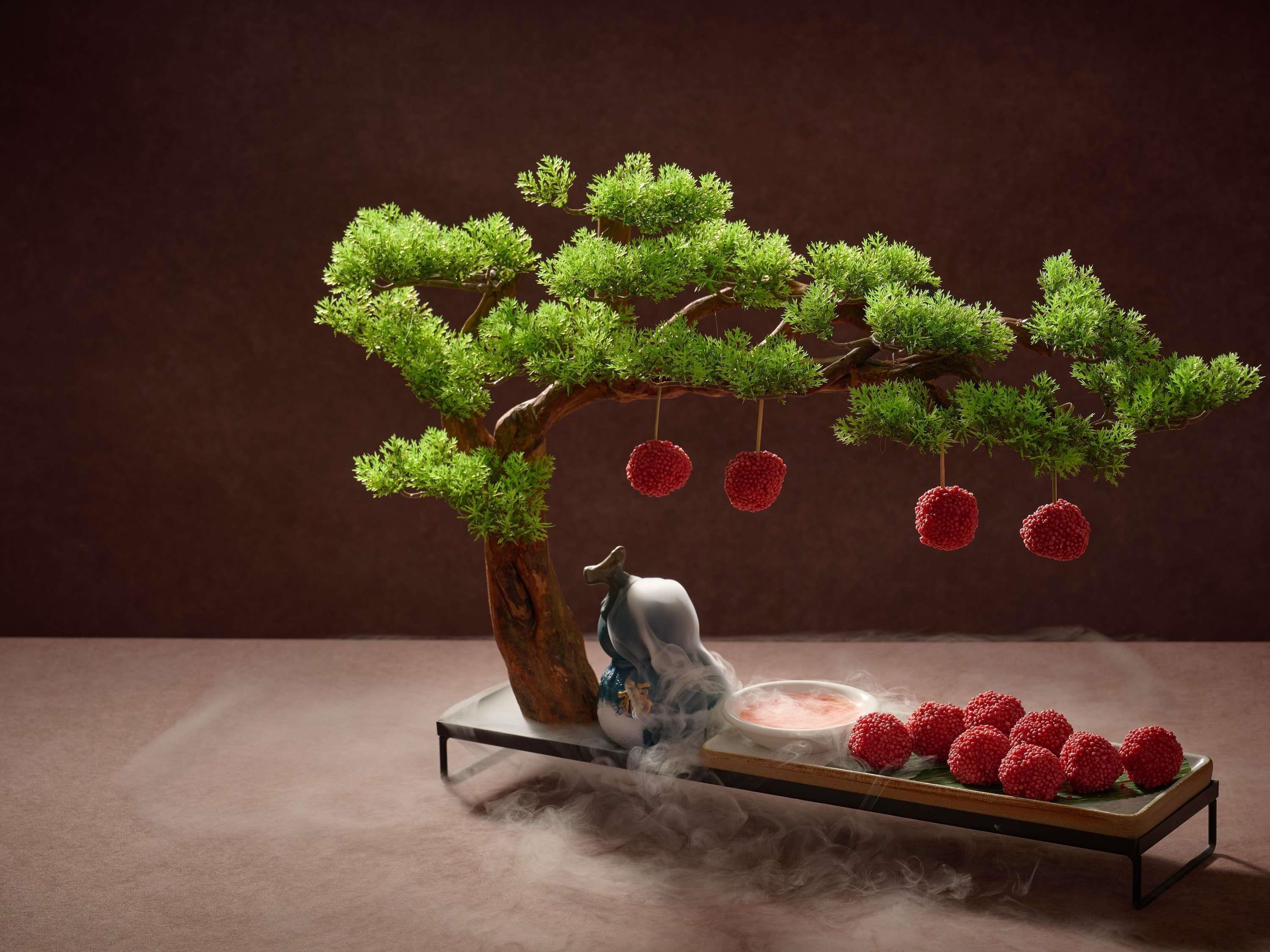 Un bonsai con frutos rojos sobre una mesa.