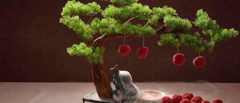 Un arbre bonsai avec des fruits rouges, posé sur une table.