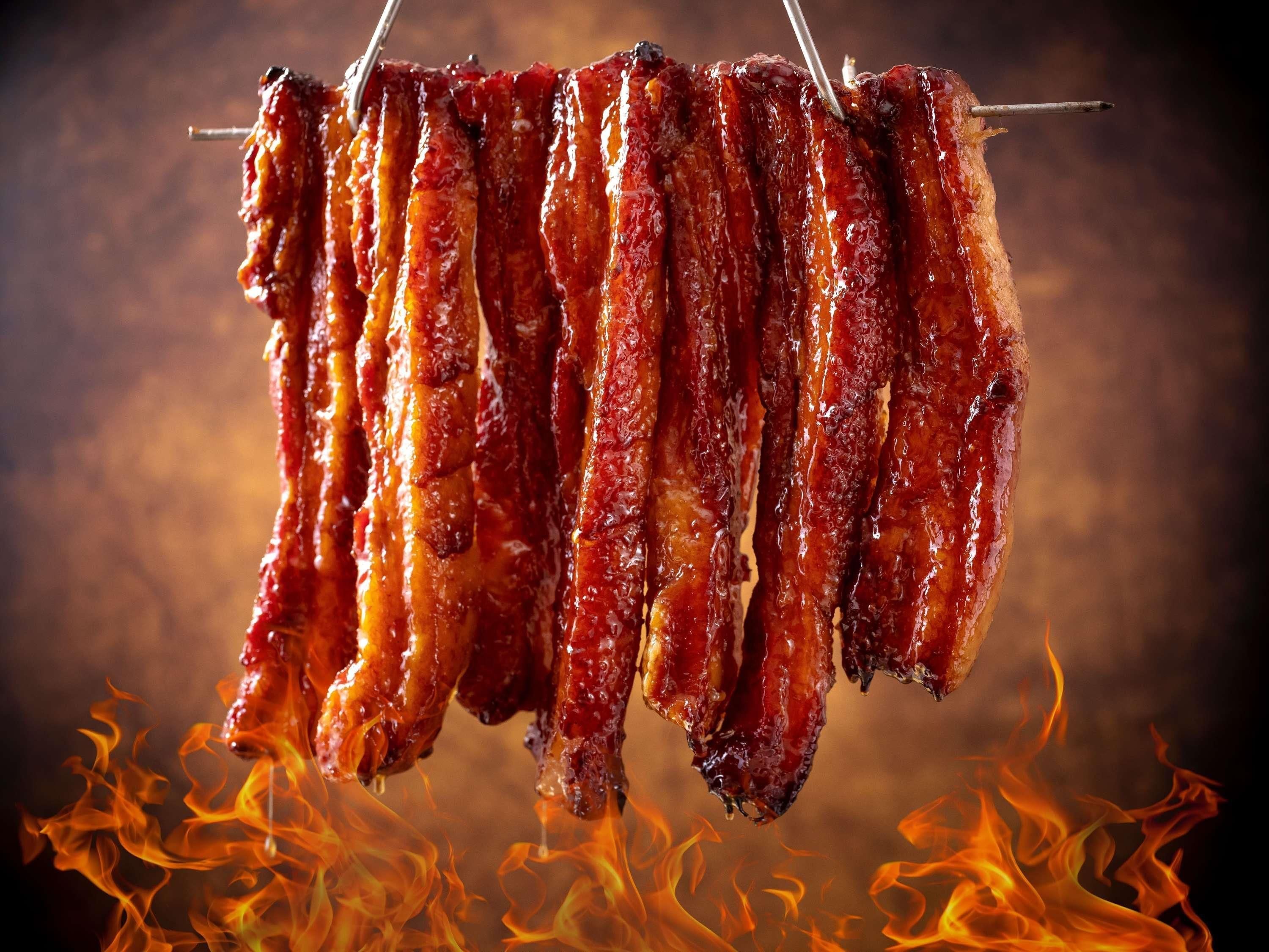 A rack of barbecued ribs hanging over a fire.