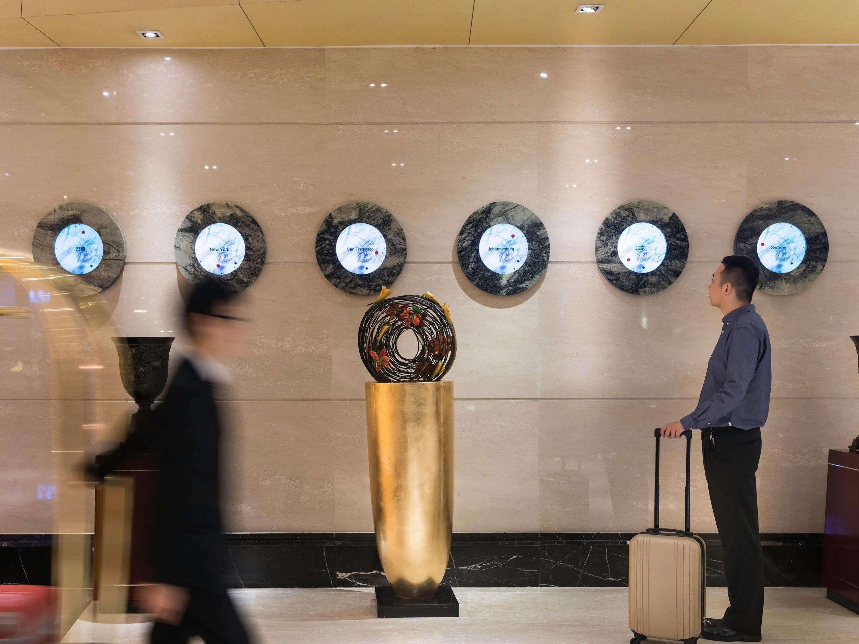 A lobby with a marble wall, a central decorative piece, and circular plaques with city names.