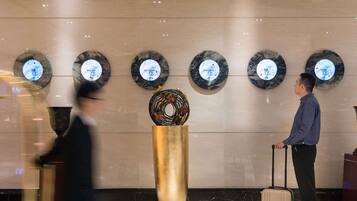 A lobby with a marble wall, a central decorative piece, and circular plaques with city names.