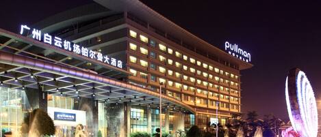 A hotel with a modern facade, multiple floors, and illuminated signage.