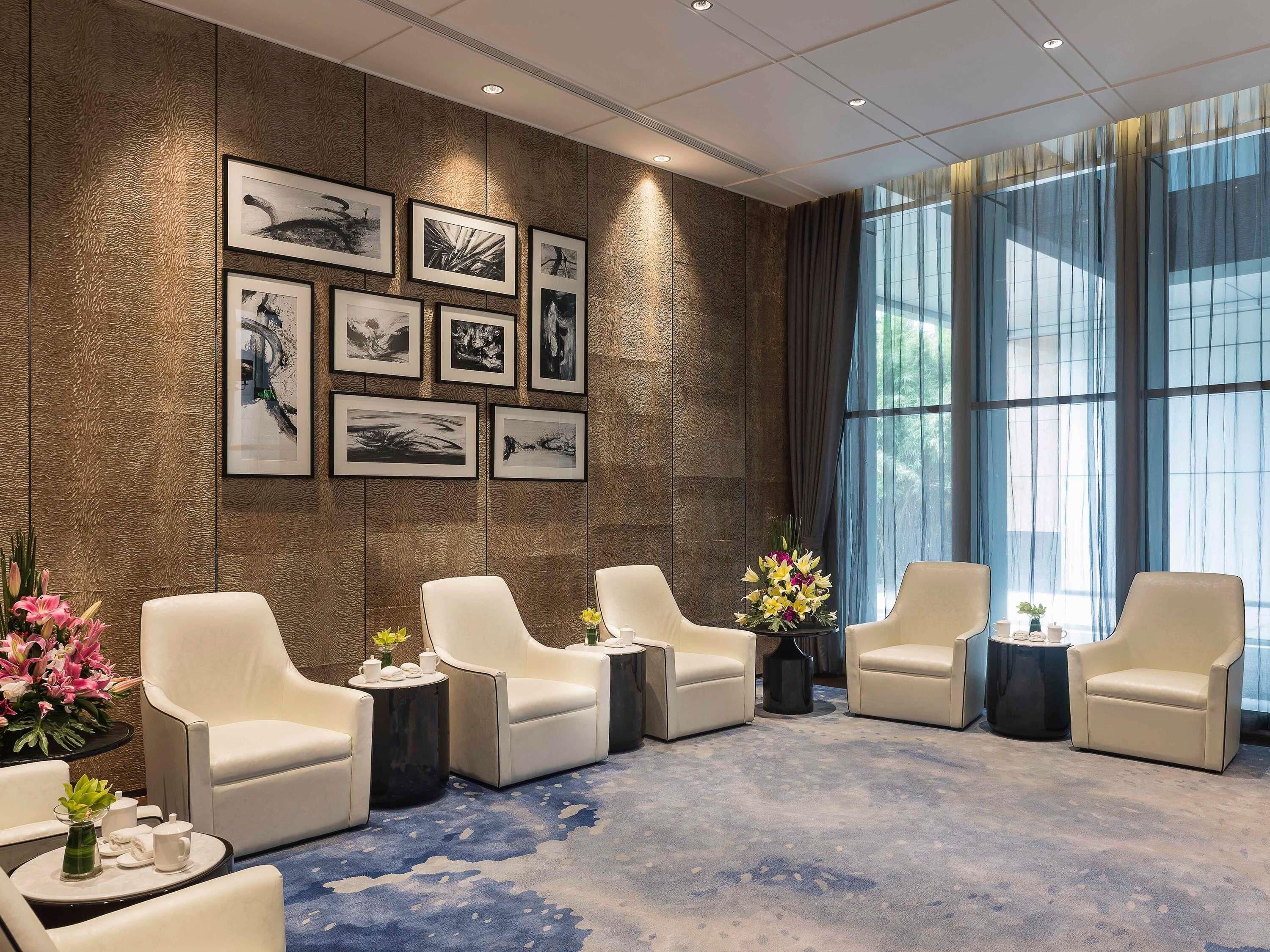 A modern lounge area with a patterned wall, framed artwork, and seating.