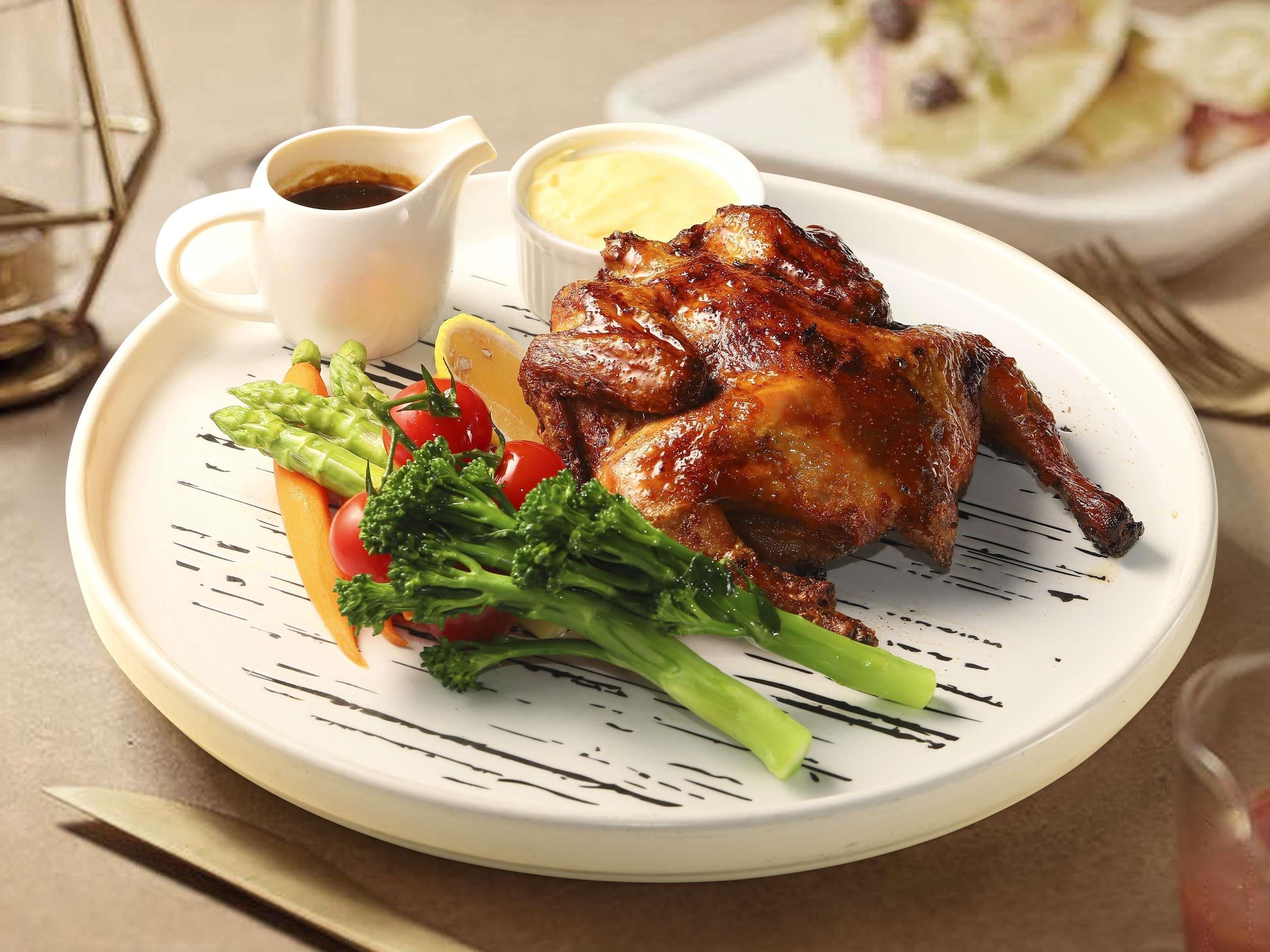 A plate with roasted chicken, vegetables, and sauces.
