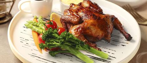 A plate with roasted chicken, vegetables, and sauces.