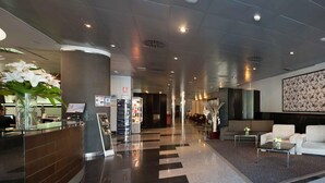 Un hall d’hôtel moderne comprenant un comptoir d’accueil, un espace salon et une signalétique directionnelle.