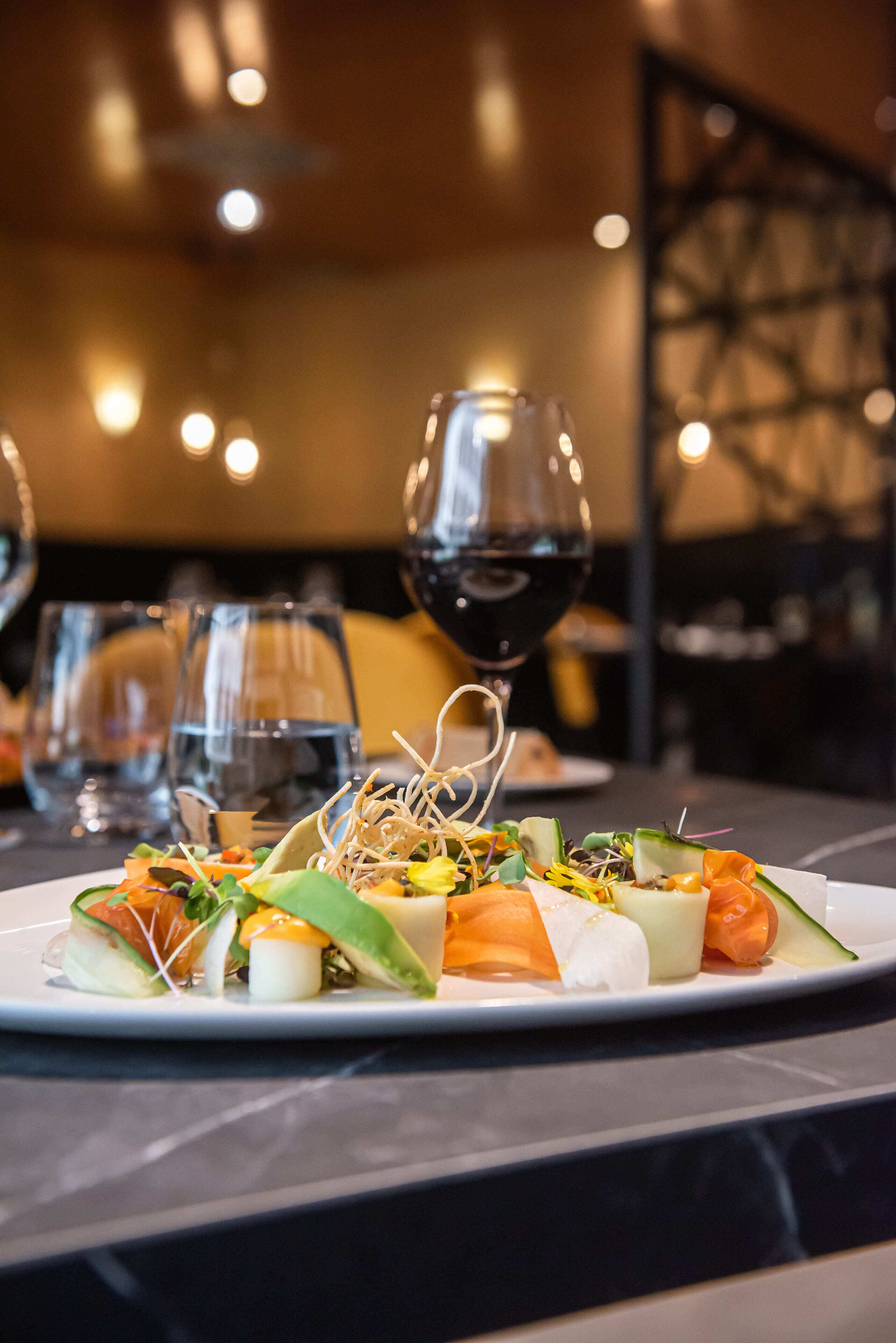 Een bord eten met verschillende groenten en een glas rode wijn op een tafel.