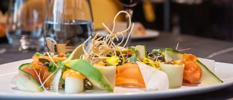 A plate of food with various vegetables and a glass of red wine on a table.