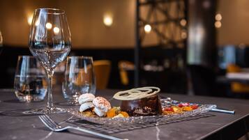 Une assiette de dessert avec un gâteau au chocolat et des guimauves, posée sur une table avec des verres à vin.