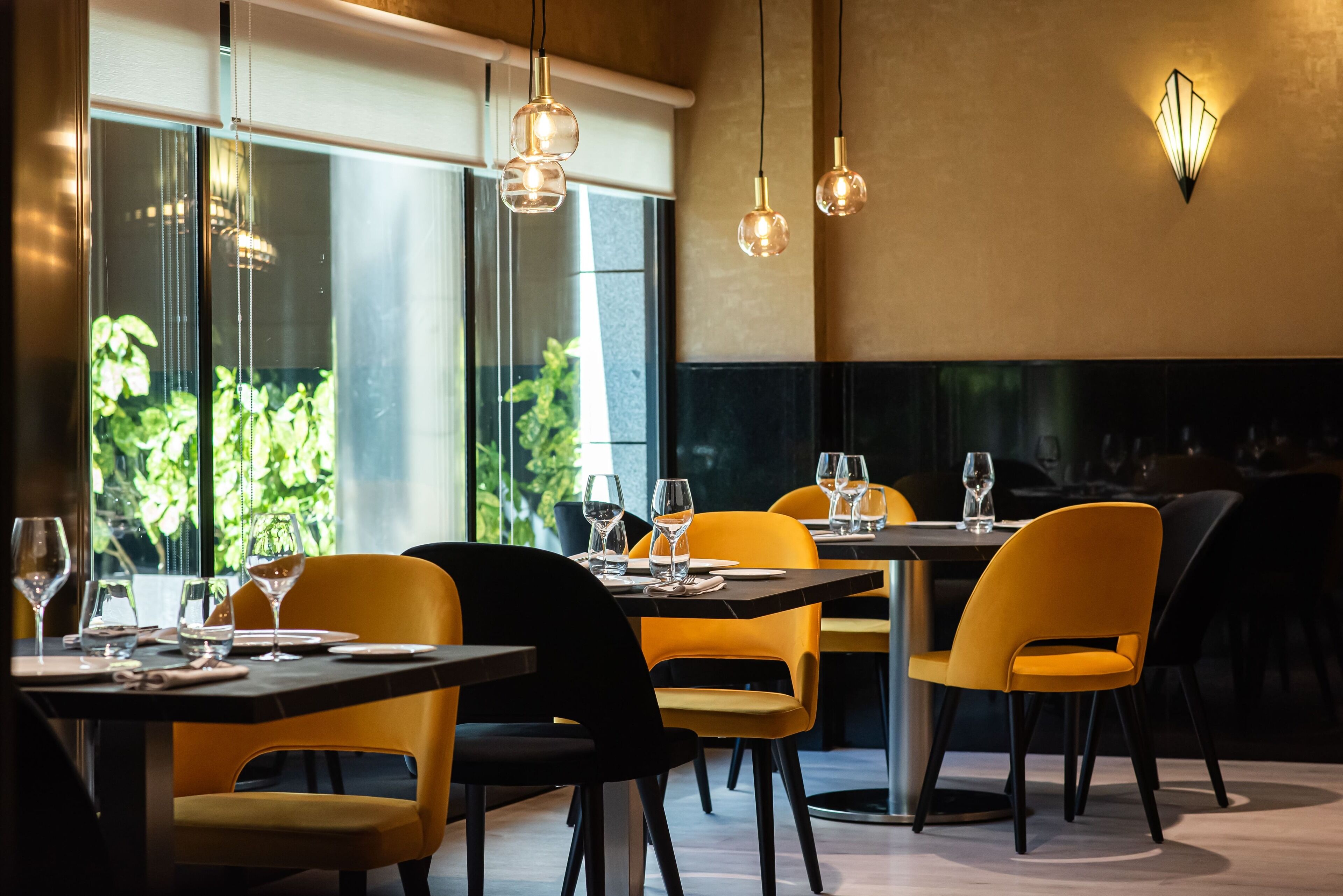 Un restaurante con mesas dispuestas para comer, sillas e iluminación colgante.