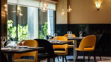 Un restaurante con mesas dispuestas para comer, sillas e iluminación colgante.