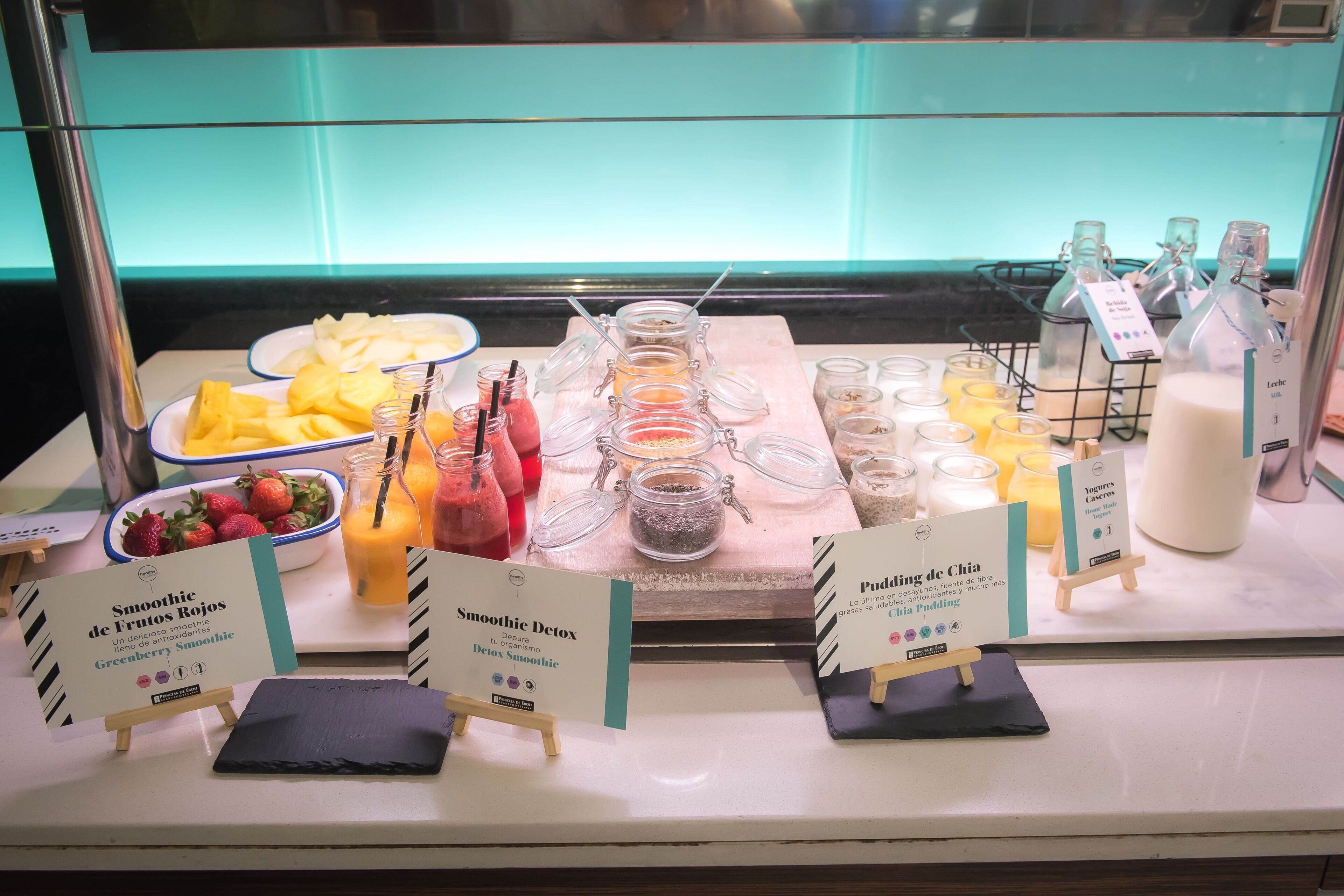 Un bufé con diversas opciones de comida y bebida, incluyendo batidos y jugos.